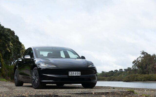 Black Tesla Model 3 Rear-Wheel Drive parked beside an estuary
