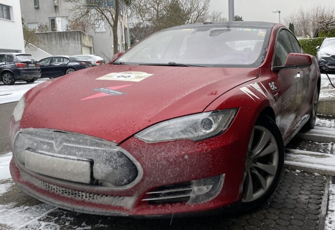 Front of a dirty red Tesla Model S in the snow