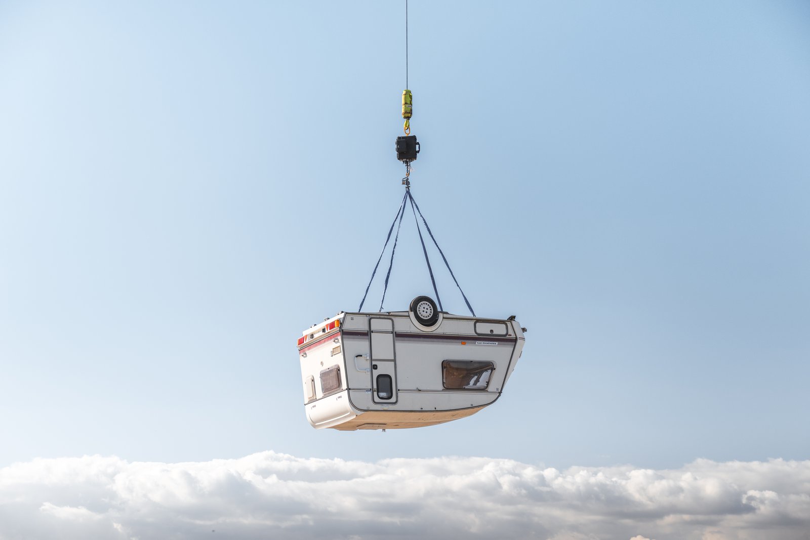 Caravan lifted high by a crane over the airfield