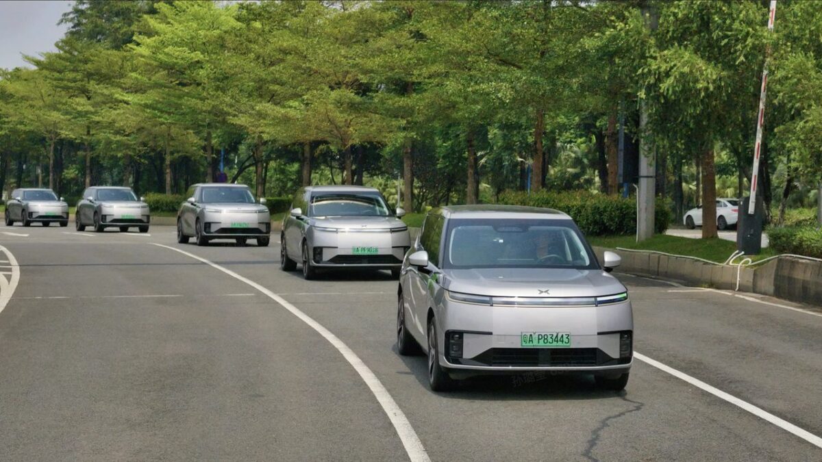 Line of silver XPeng robotaxis driving on a tree-lined road in Guangzhou
