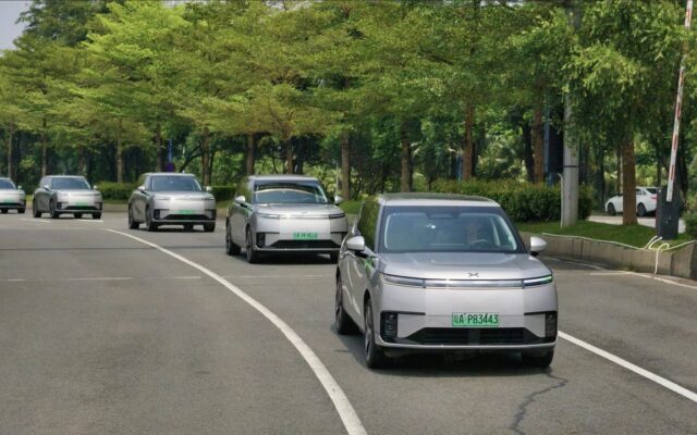 Line of silver XPeng robotaxis driving on a tree-lined road in Guangzhou